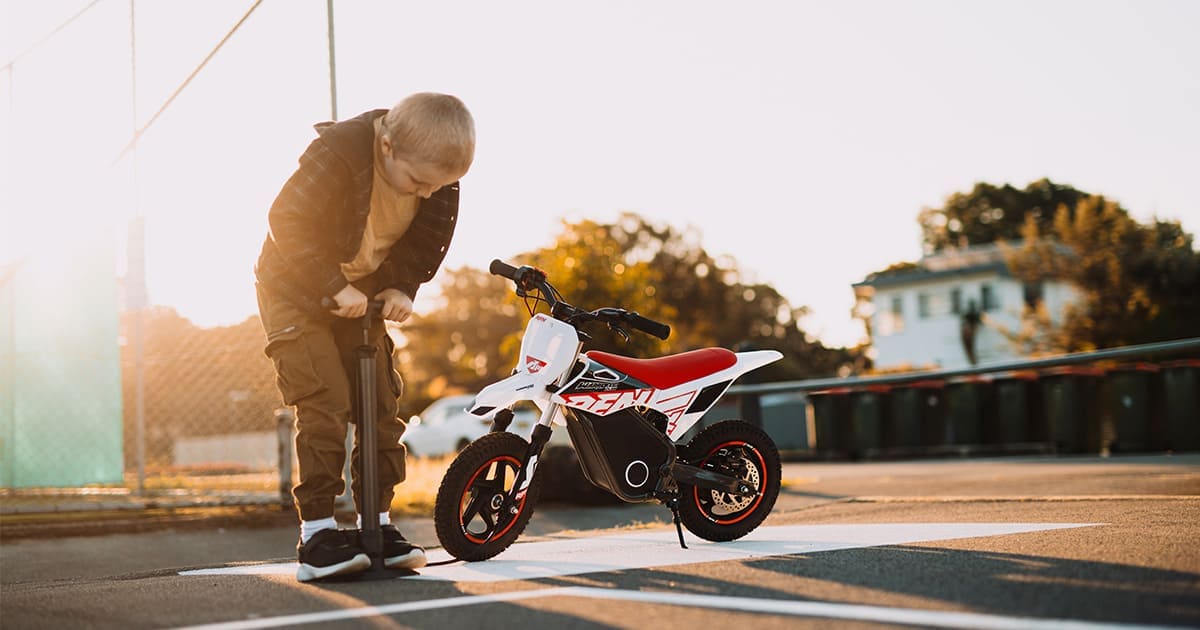 A little boy is inflating his dirt bike with an inflator