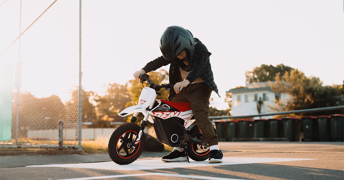 a boy sitting on his dirt bike looking down at his dirt bike