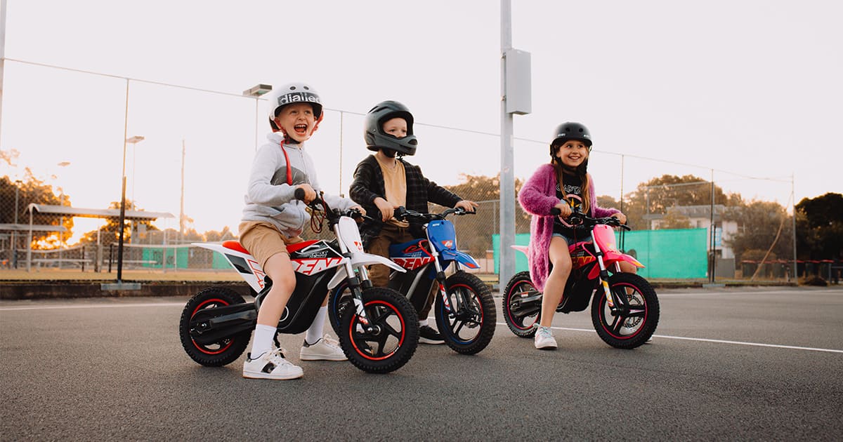 three children are riding their dirt bike happily