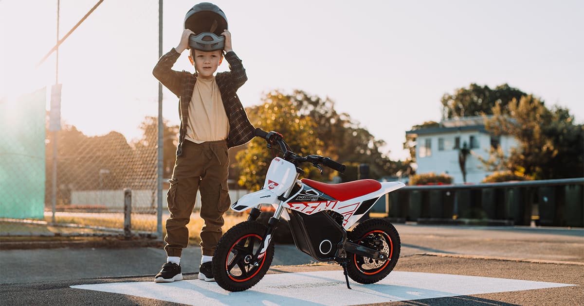 a boy is wearing a helmet next to his dirt bike